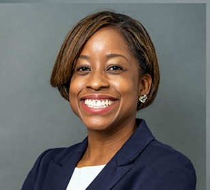 a woman with short hair, wearing a smart black jacket and white top, smiling 